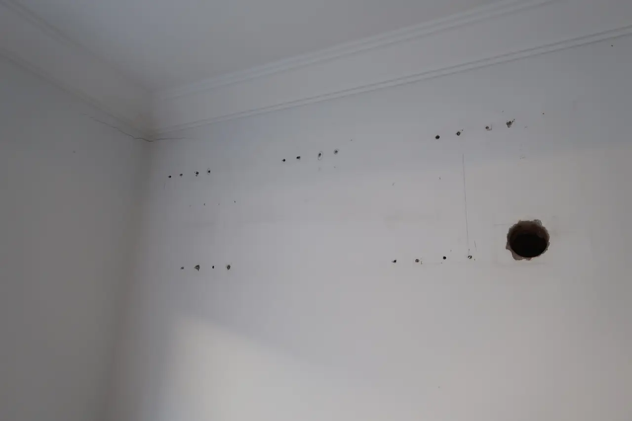 Bedroom wall with several small holes and one large hole, before repair