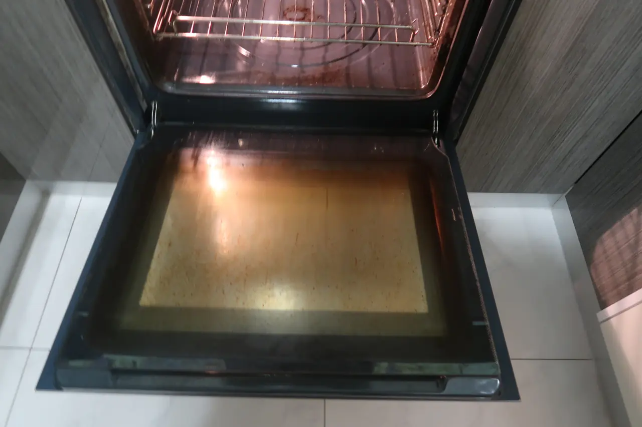 Oven interior with no tray in, heavy grease and stains on the floor, before cleaning